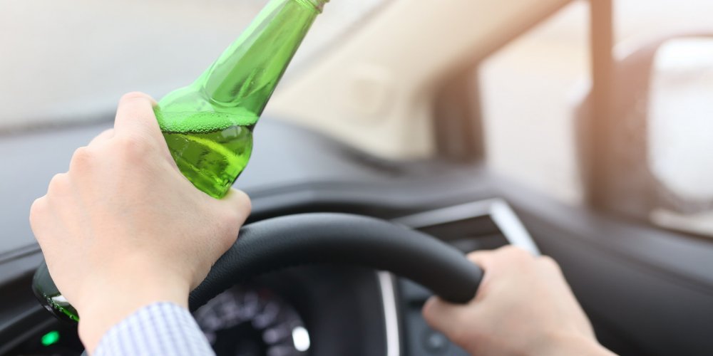 Driving under influence with bottle in hand.